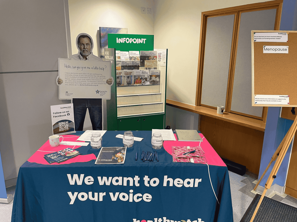 Image of the setup of Healthwatch Lancashire, it's a table with a blue and pink blanket on with leaflets and resources. 