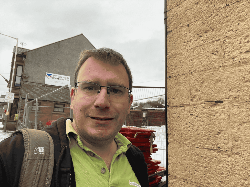 image of engagement team leader Steve outside in front of a sign that says veterans in communities. 