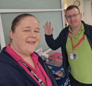 Emmy and Steve in front of a healthwatch branded table at Chorley and South Ribble hospital